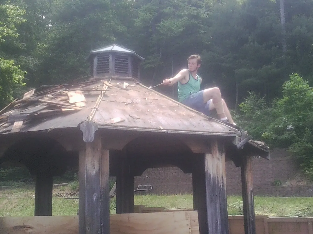 Tearing the old roof off a wooden gazebo before new shakes in Valley