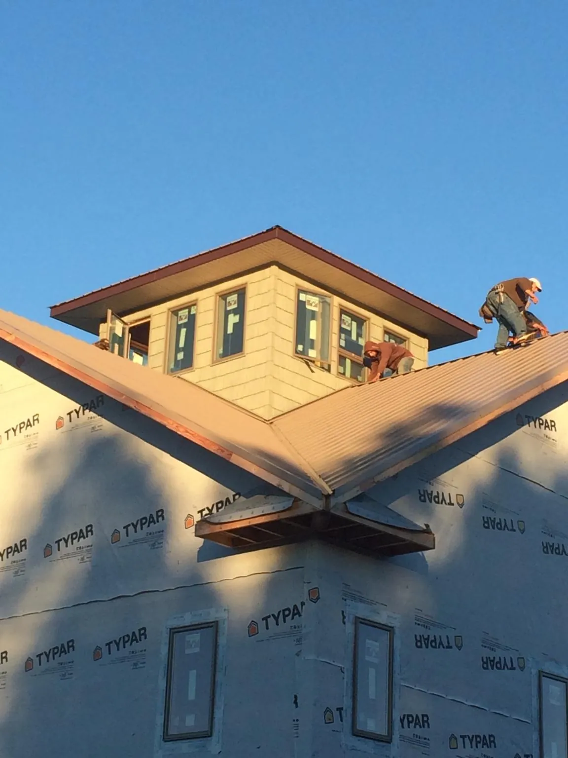 Roofers working around a rooftop cupola on a new metal roof at sunset — Roof Waterproofing in Valley by Roofing Brothers